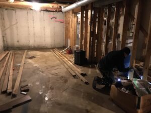 An electrician performing electrical rough-in work in a basement under construction for Dylco Electric in Westfield, IN