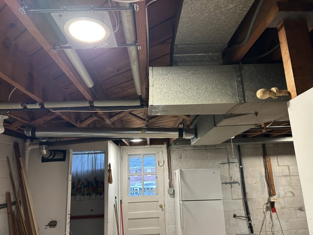 Exposed electrical wiring and conduit installed on a basement ceiling by Common Ground Electrical in Baltimore, MD.