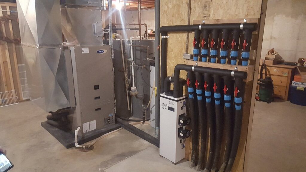 A complex basement HVAC system, including a Carrier furnace and manifold, installed by Custom Climates in Iowa City, IA.