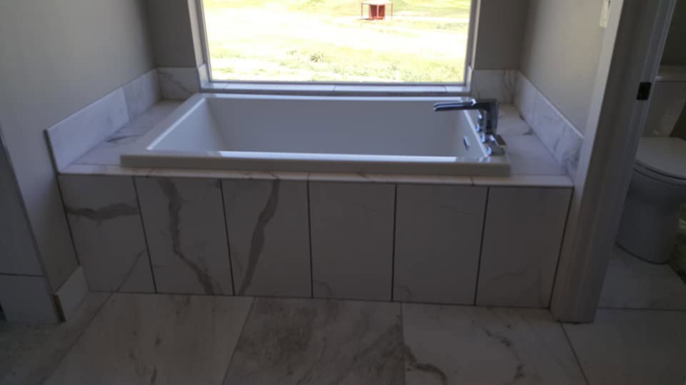 A bathroom with a newly installed bathtub and surrounding tile work by Carpet Planet LLC in Colorado Springs, CO.