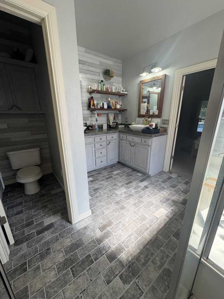 A modern bathroom with dark grey brick-patterned tile flooring installed by Carpet Direct Brandon Burley in Muskogee, OK