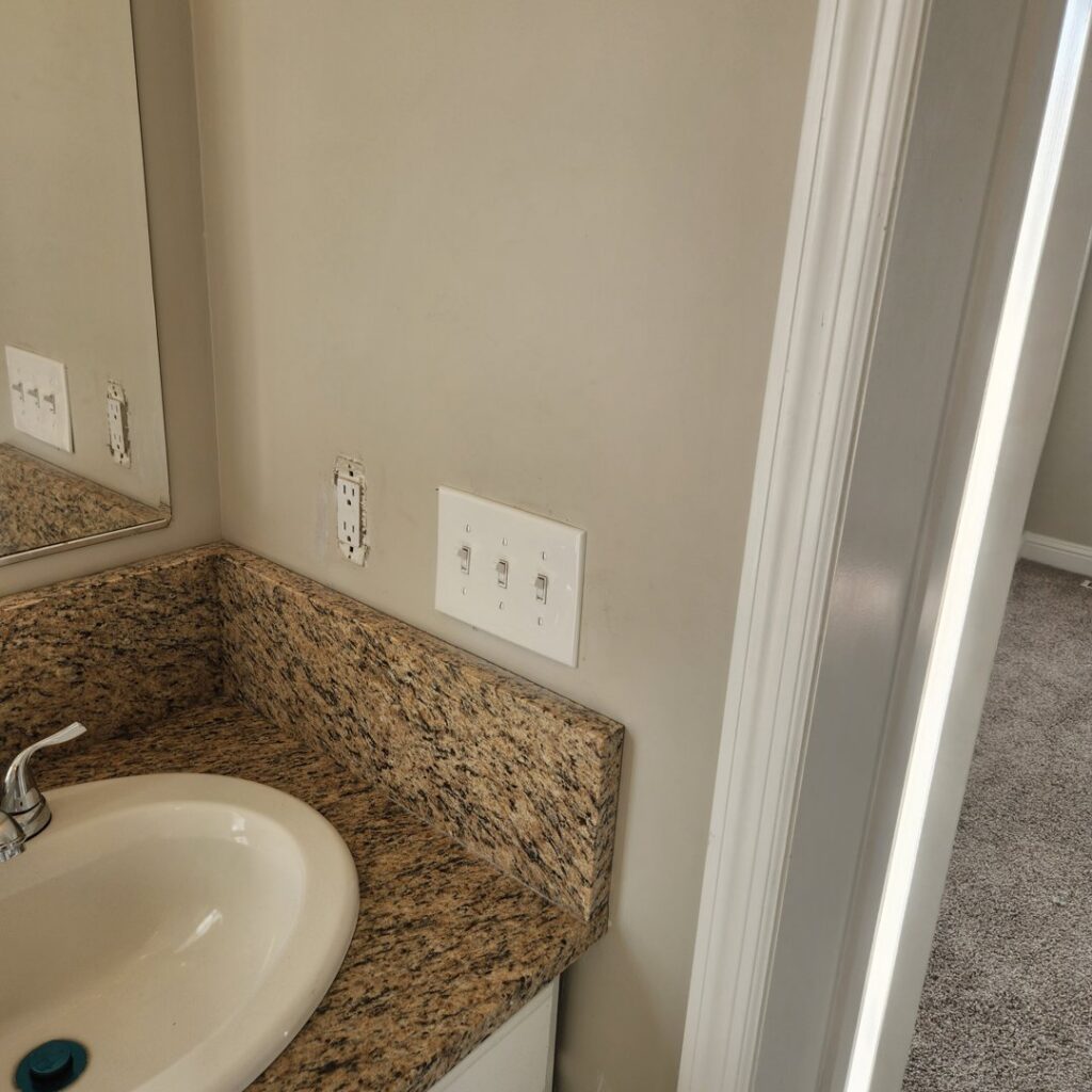 Bathroom wall showing electrical outlets and light switches during installation by Tim Lambert Electric in Fayetteville, NC.