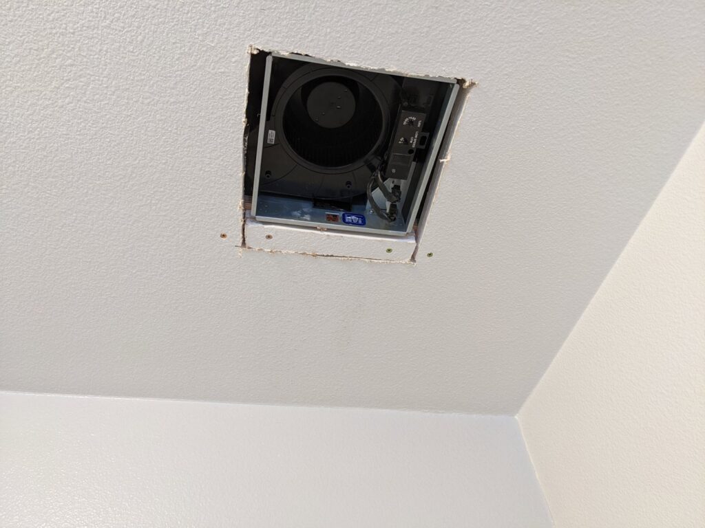 An exposed bathroom exhaust fan being installed or repaired, a service offered by Primo's Electrical Services in San Diego, CA.