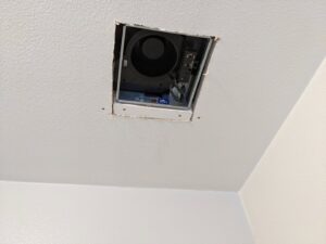 An exposed bathroom exhaust fan being installed or repaired, a service offered by Primo's Electrical Services in San Diego, CA.
