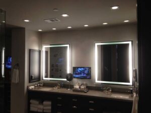 A modern bathroom featuring illuminated mirrors and recessed lighting installed by Christensen Electric in Galveston, TX.