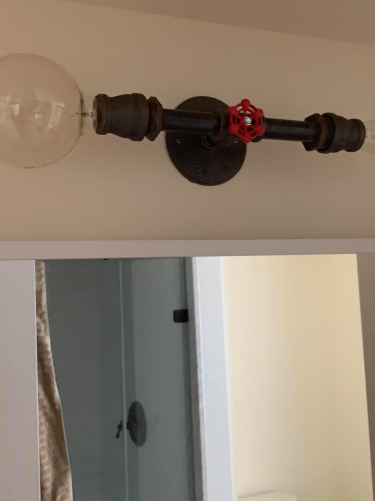 Newly installed industrial-style bathroom light fixture by A.C. & Son's Electric LLC in Pawtucket, RI
