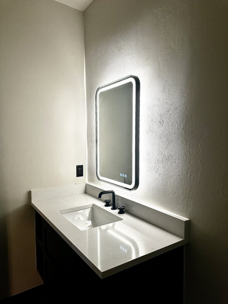 A modern bathroom vanity with a sleek lighted mirror installed by Premier Power in Edmond, OK.