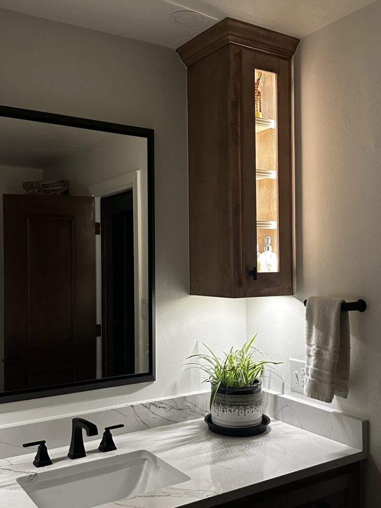 A modern bathroom vanity featuring lighted cabinet and under-cabinet lighting installed by Premier Power in Edmond, OK.