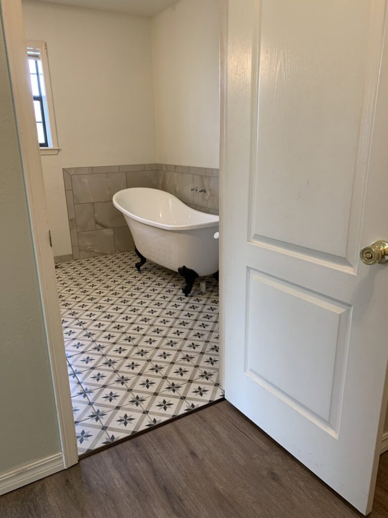 A bathroom with elegant patterned tile flooring and a clawfoot tub installed by Carpet Direct Brandon Burley in Muskogee, OK