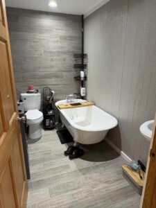A stylish bathroom with grey plank tile flooring and a clawfoot tub installed by Carpet Direct Brandon Burley in Muskogee, OK