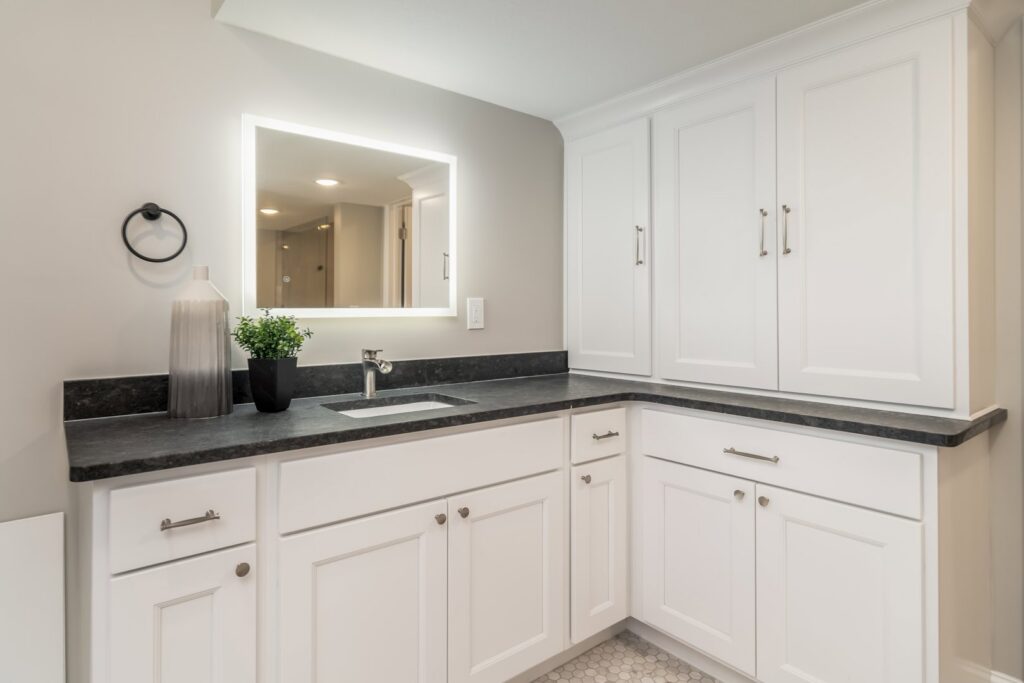 Bathroom vanity with an illuminated mirror and modern lighting fixtures installed by Innovative Electric in Wichita, KS.