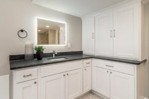 Bathroom vanity with an illuminated mirror and modern lighting fixtures installed by Innovative Electric in Wichita, KS.