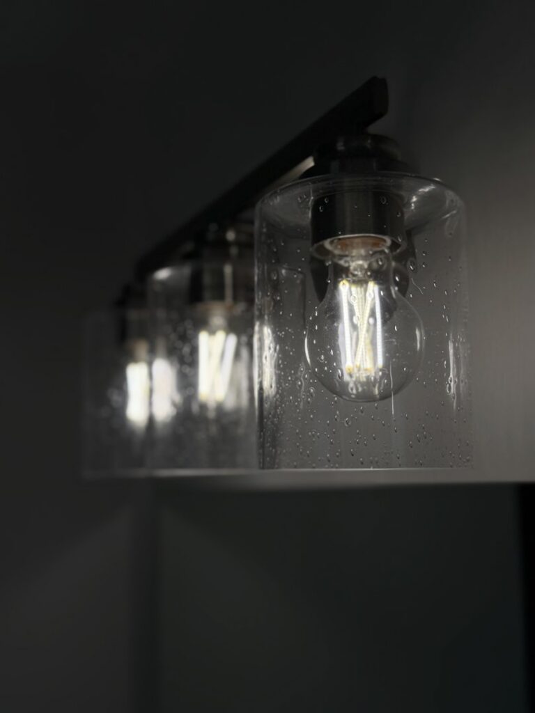 A modern bathroom vanity light fixture with Edison-style bulbs installed by Precision Electric and Lighting Services in Olive Branch, MS.