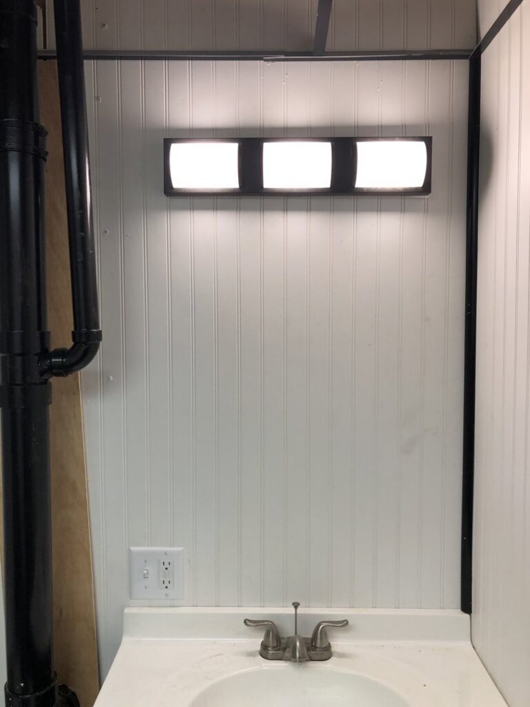 A newly installed bathroom vanity light fixture and electrical outlet above a sink by Surge Electric LLC in Youngstown, OH.