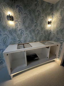 A newly installed bathroom vanity with modern wall sconces and under-cabinet lighting by Ampler Electrical Services in Wilmington, NC.