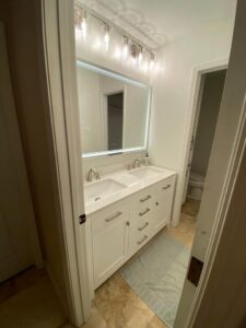 A modern bathroom vanity with a lighted mirror and new light fixture installed by Greater Baton Rouge Electric in Baton Rouge, LA.