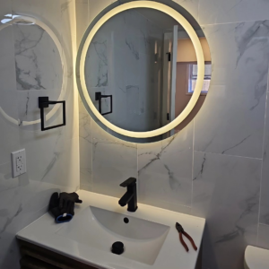 A bathroom vanity with an illuminated mirror and electrical outlet installed by C&J And Sons Multi Services in Newark, NJ.