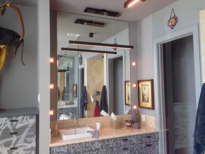 A bathroom vanity with modern linear lighting fixtures and accent wall lights installed by Christensen Electric in Galveston, TX.