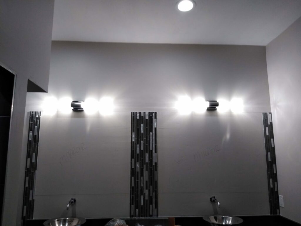 A finished bathroom featuring modern vanity lights and recessed ceiling lighting installed by The Specialist Electrical Contractor in Albuquerque, NM.