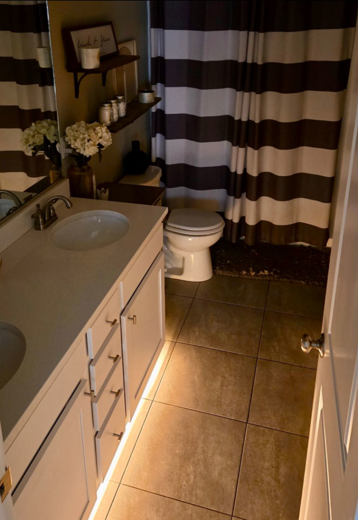 A bathroom vanity featuring elegant under-cabinet strip lighting installed by Woodford Power & Light Co. in Ankeny, IA.