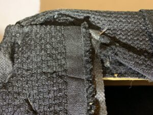 Small brown specks, likely bed bug evidence, on black fabric, showing a pest inspection by Pros In Control Pest Services in Jersey City, NJ.