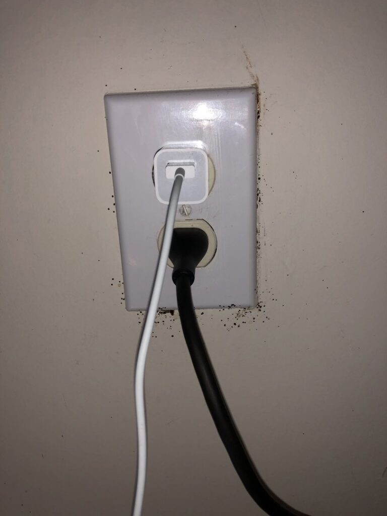 Bed bug fecal stains visible around an electrical outlet, a common hiding spot addressed by Himalaya Pest Control in Alpharetta, GA.