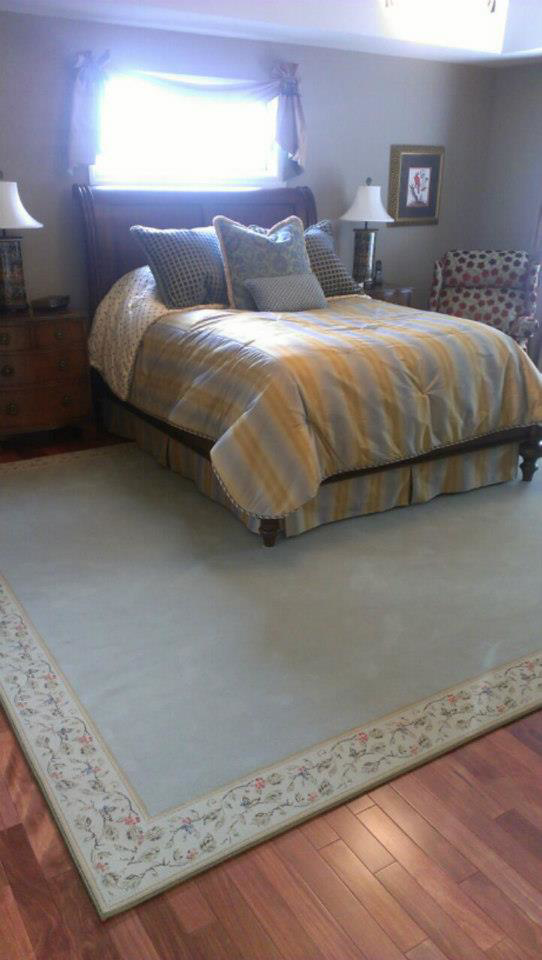 A bedroom featuring a large area rug with an elegant floral border from Carpet Art of America in O'Fallon, MO.