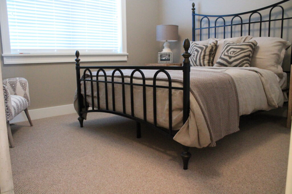 A bedroom showcasing wall-to-wall carpet with a vibrant red area rug, installed by Rich's Modern Flooring in Billings, MT.