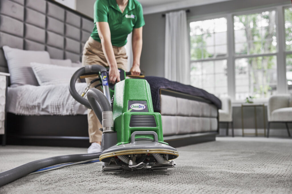 A technician from Brooke's Chem-Dry Lawrence cleaning a bedroom carpet with a professional machine in Kansas City, MO.