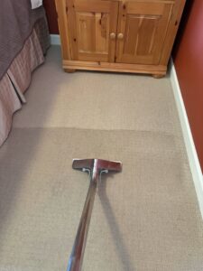 A professional cleaning wand actively cleaning a light-colored bedroom carpet, demonstrating Soft N Dry's service in Tucson, AZ.