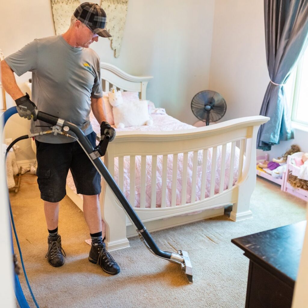 A professional cleaning bedroom carpet with a specialized wand for Renew Cleaning Services in Scottsdale, AZ.