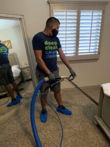 A DEEP CLEAN Carpet Cleaners professional cleaning bedroom carpet while wearing shoe covers in Beaverton, OR