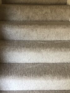 A newly installed light gray carpet in a bedroom with a bed and ottoman by BC Quality Flooring in Jeffersonville, IN.