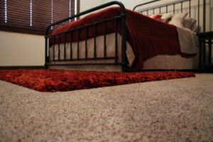 A neatly carpeted bedroom with a metal bed frame, a project by Rich's Modern Flooring in Billings, MT.