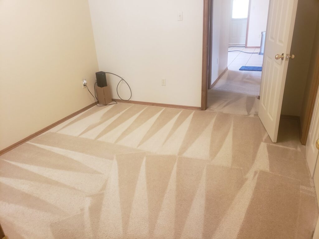 A bedroom carpet showing clear cleaning lines after a professional service by A Plus Carpet Cleaning in Lawton, OK.
