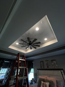 A bedroom ceiling with a fan and recessed lights, indicating electrical installation by Llanos Electric Builders in Houston, TX.