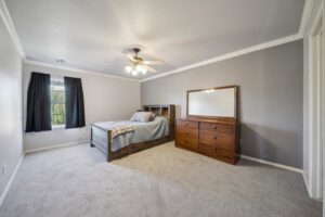 A cozy bedroom featuring a new gray carpet installation, showcasing quality work by B A Carpet and Flooring in Broken Arrow, OK.