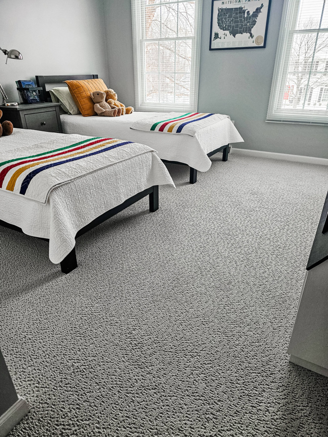 A cozy bedroom featuring a fresh grey carpet installation by Absolute Floor Covering, Inc in Kentwood, MI.