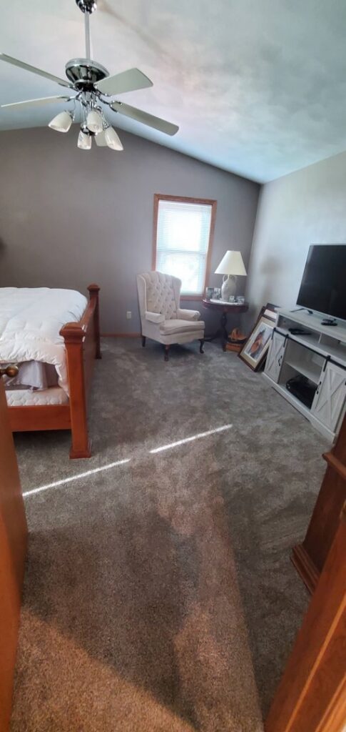 A cozy bedroom with a new grey carpet installation completed by PCS Flooring LLC in Appleton, WI.