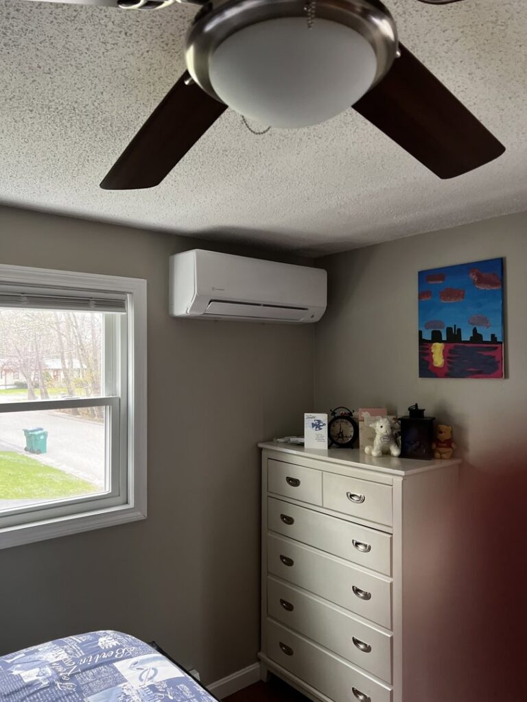 An indoor mini-split air conditioning unit installed in a bedroom above a dresser, showcasing work by A&D Ductless LLC in Lunenburg, MA.