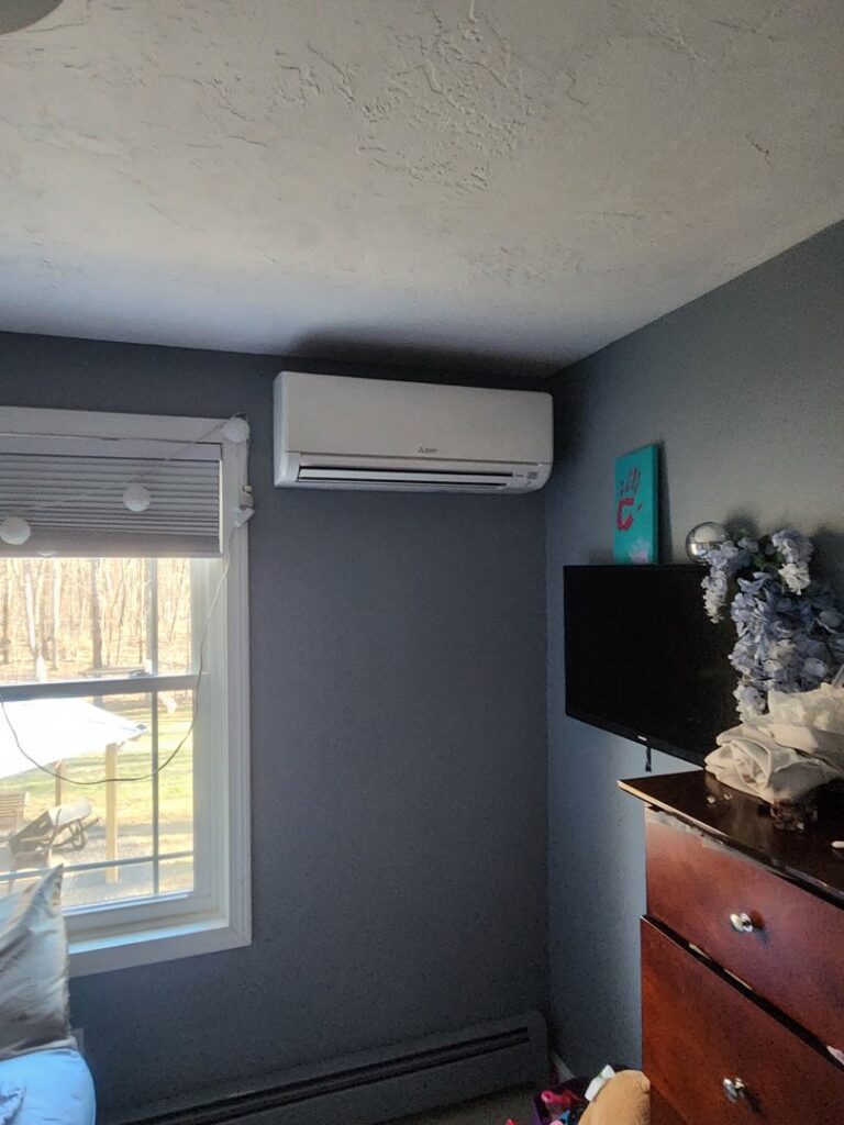 A white mini-split air conditioning unit installed on a bedroom wall by C & C Temp Control in Worcester, MA.