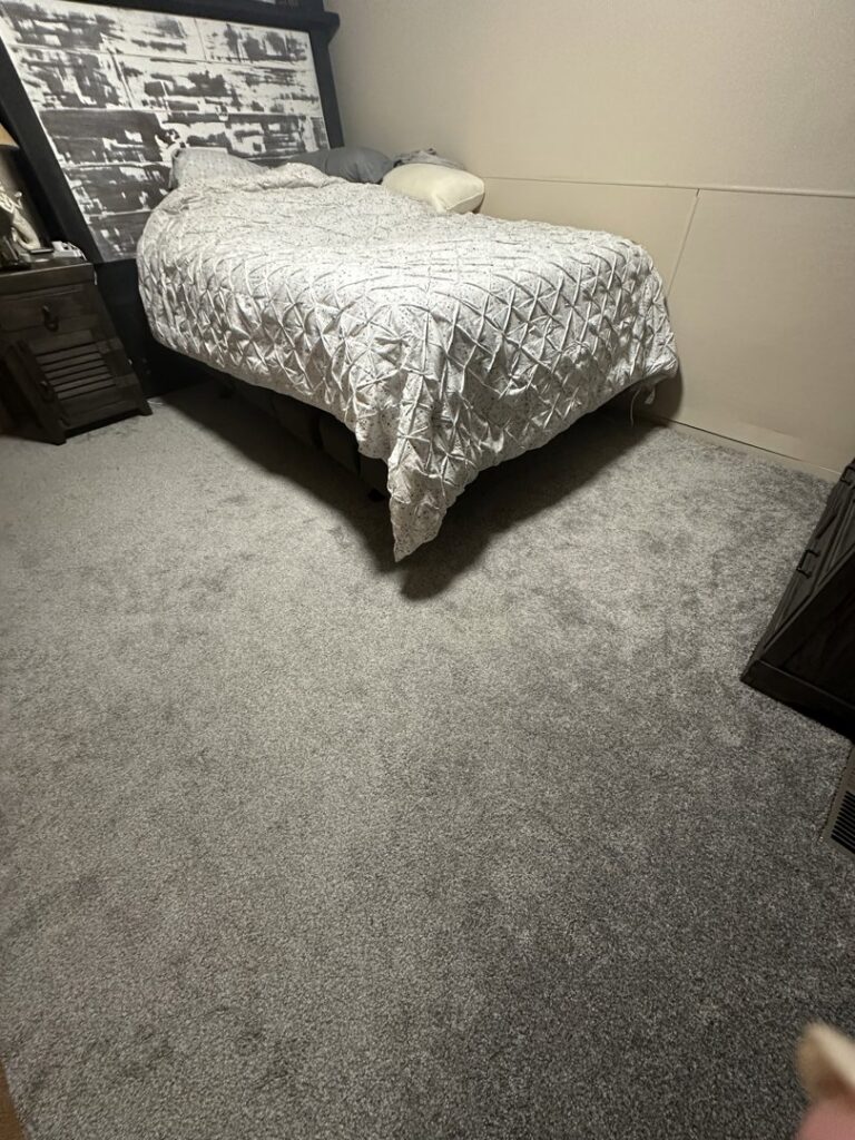 A bedroom showcasing newly installed plush grey carpet, expertly laid by Home Dynamics Flooring LLC in Harrisburg, SD.