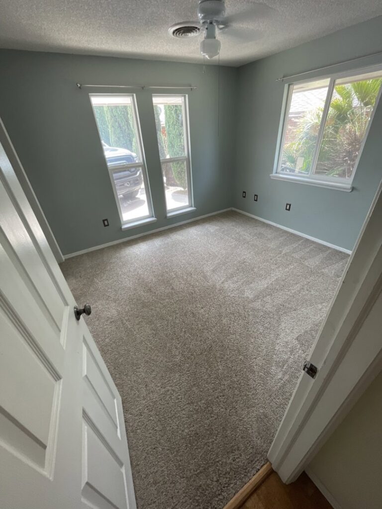 A bedroom with a clean carpet and bright windows, showcasing work by Alamogordo Carpet Cleaning in Alamogordo, NM.