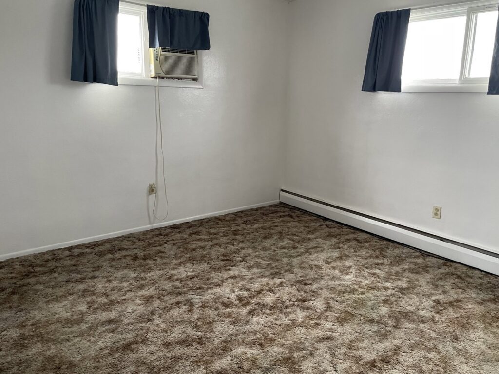 A bedroom featuring a dirty, matted brown carpet, indicating a need for professional cleaning by KANDE Carpet Cleaning in Pittsburgh, PA.