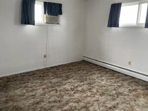 A bedroom featuring a dirty, matted brown carpet, indicating a need for professional cleaning by KANDE Carpet Cleaning in Pittsburgh, PA.
