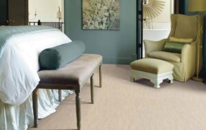 A cozy bedroom featuring light-colored textured carpet installed by Carpets Plus Cabinets Plus in St. Louis, MO.