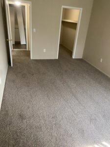 A cozy bedroom showcasing new grey carpet installed by Red carpet&home remodeling, a professional carpet contractor in Olney, MD.