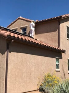 A beekeeper on a residential roof inspecting the eaves for pest activity by Southwest Pest Solutions in Tucson, AZ