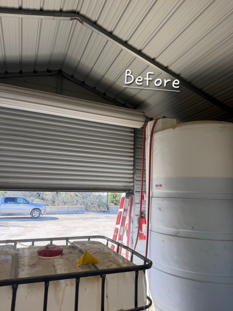 An interior 'Before' view of a partially open roll-up garage door, indicating a repair or installation job for Atomic Door Service in Tulsa, OK.