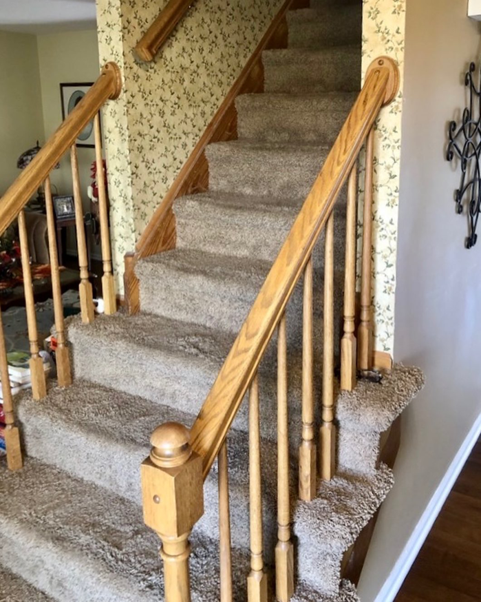 A beige carpeted staircase with a wooden handrail, showcasing carpet work by GC&D Flooring in Allentown, PA.